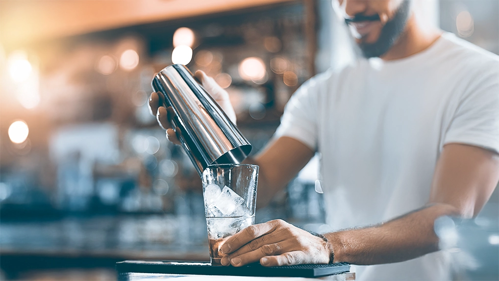 Expert barman making cocktail at night club cocktail shaker.