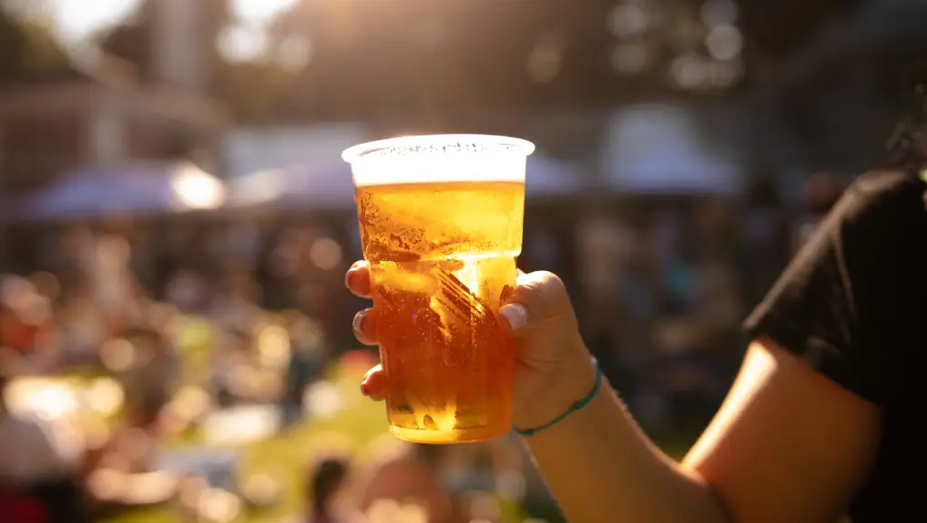 image of Person holding beer cup outdoors on a sunny day.