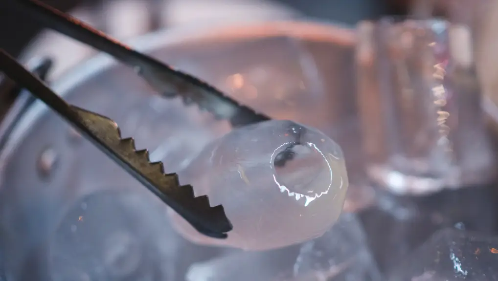 image of close up ice bucket with hand holding Ice is a clean tongs and sensitive focus