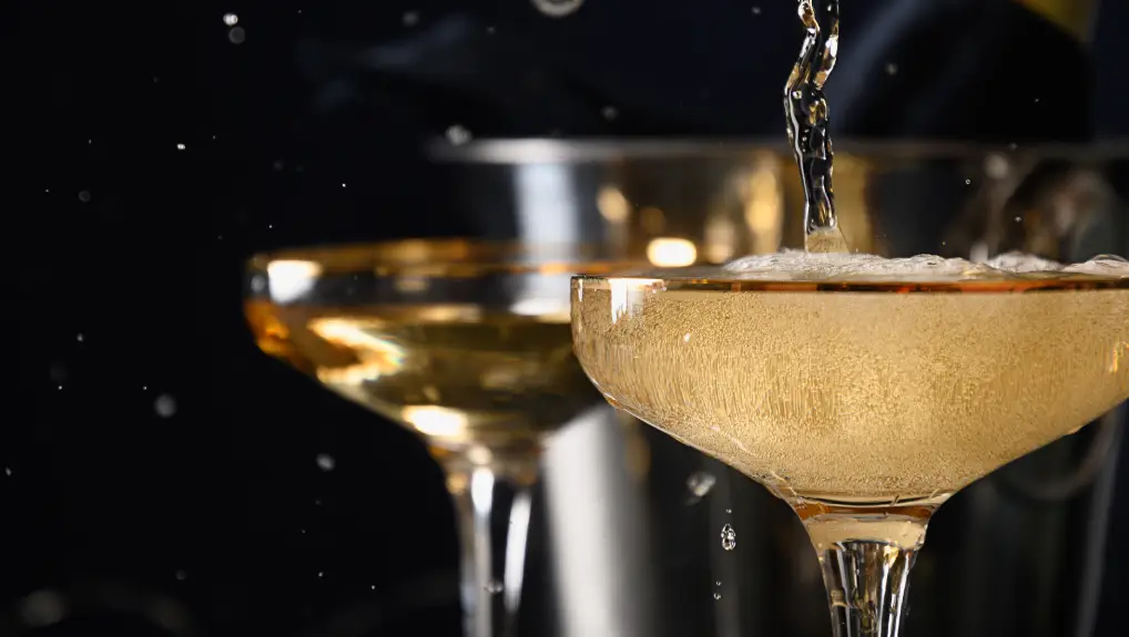 image of Pouring champagne to wine glasses on black background