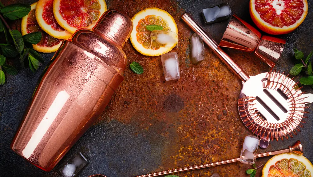 Image of Bar accessories, drink tools and cocktail ingredients - red oranges, lime, minta and ice cubes on rusty stone table.
