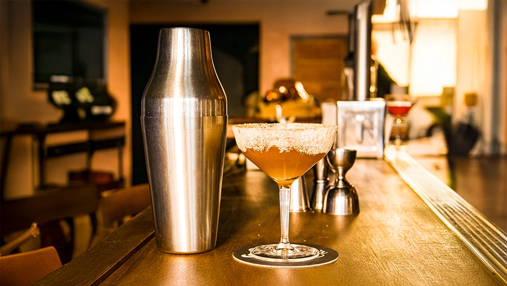 image of parisian shaker with cocktail at a warmly lit bar scene