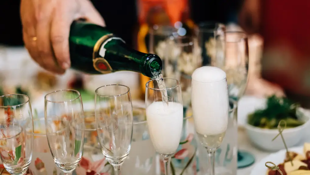 pours champagne in a glass