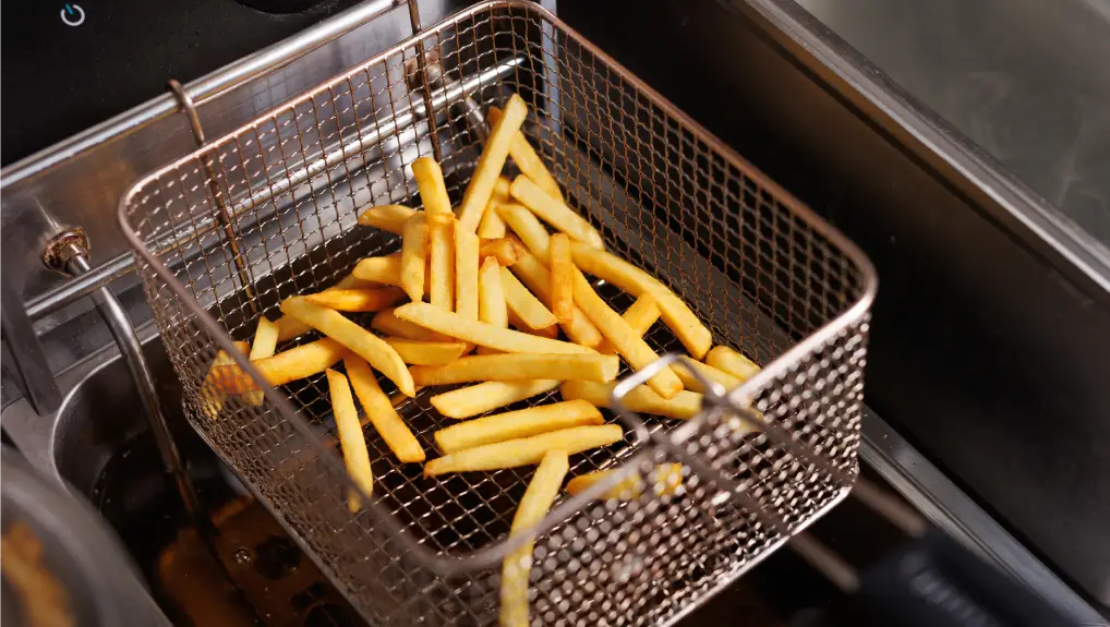 Frying potatoes in fryer for french fries in a restaurant