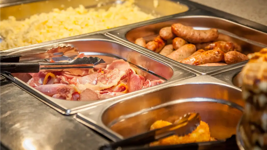 Hot counter with gastronormcontaining warm breakfast items such as scrambled or fried eggs, bacon, sausages, grilled tomatoes