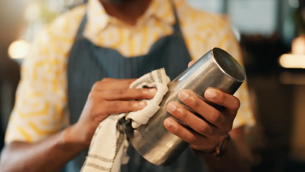 Image of a Bartender, hands and man with mug, wiping and cleaning with routine, cloth and process
