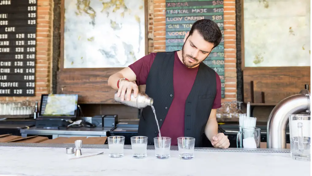 Confident bartender serving cocktails in glasses on counter at restaurant