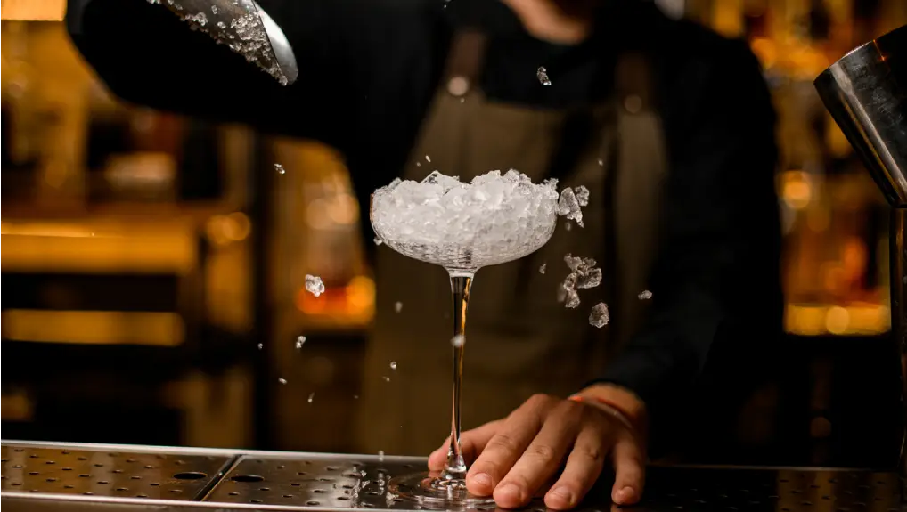 close up image of a bartender filling a cocktail glass with crushed ice displaying the right ice tools for a bar