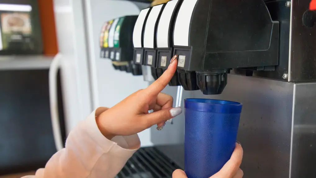 image of  pours a fizzy drink into a blue glass from a Soda Gun System