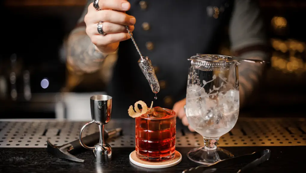 close image of a bartender crafting a cocktail with expert knowledge of the role of bar tools