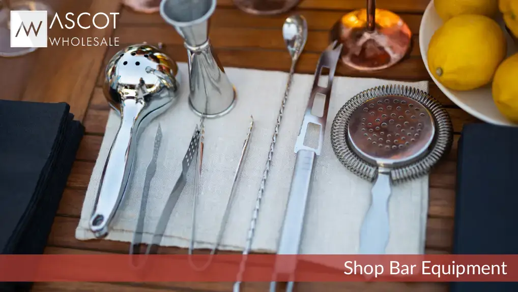 Close up image of must have bar tools for crafting cocktails including strainer, jigger.
