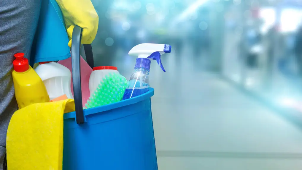 leaning lady with a bucket and cleaning products on blurred background .