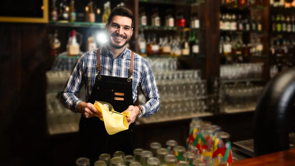 Image of happy bartender cleaning the drinking glass.