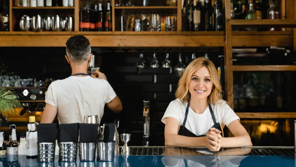 Image of two bartenders behind a well stocked bar that followed the step by step guide to setting up a commercial bar
