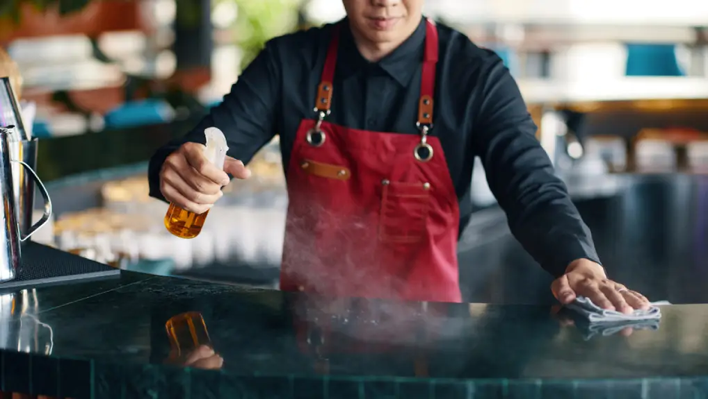 Image of a bartender cleaning a commercial bar and equipment