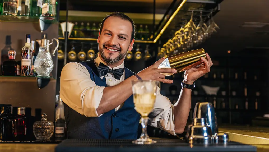 Image of Smiling Bartender Making Cocktail In Bar with his preferred shaker