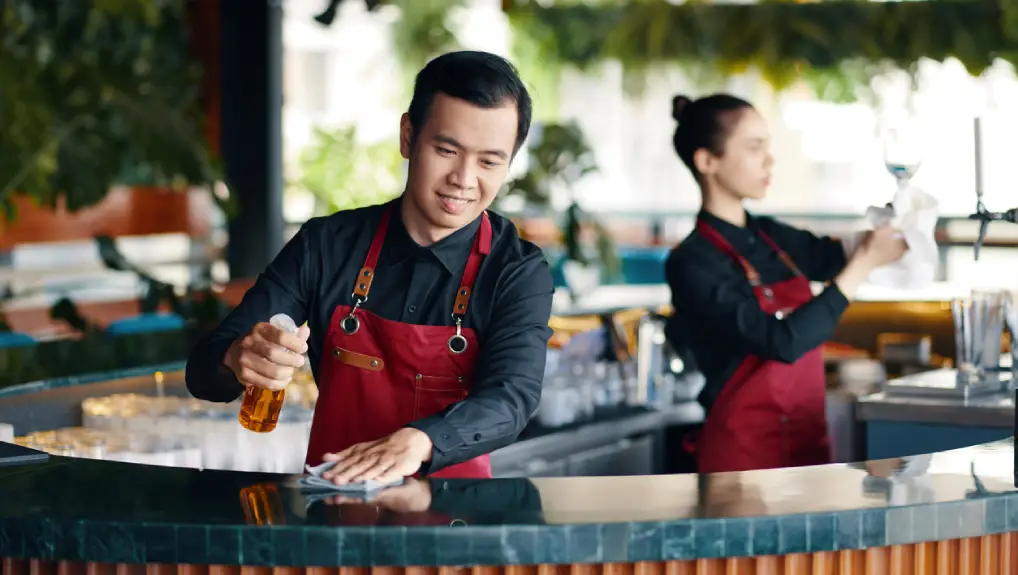 Image of a bar area with two bartender maintaining the bar area.