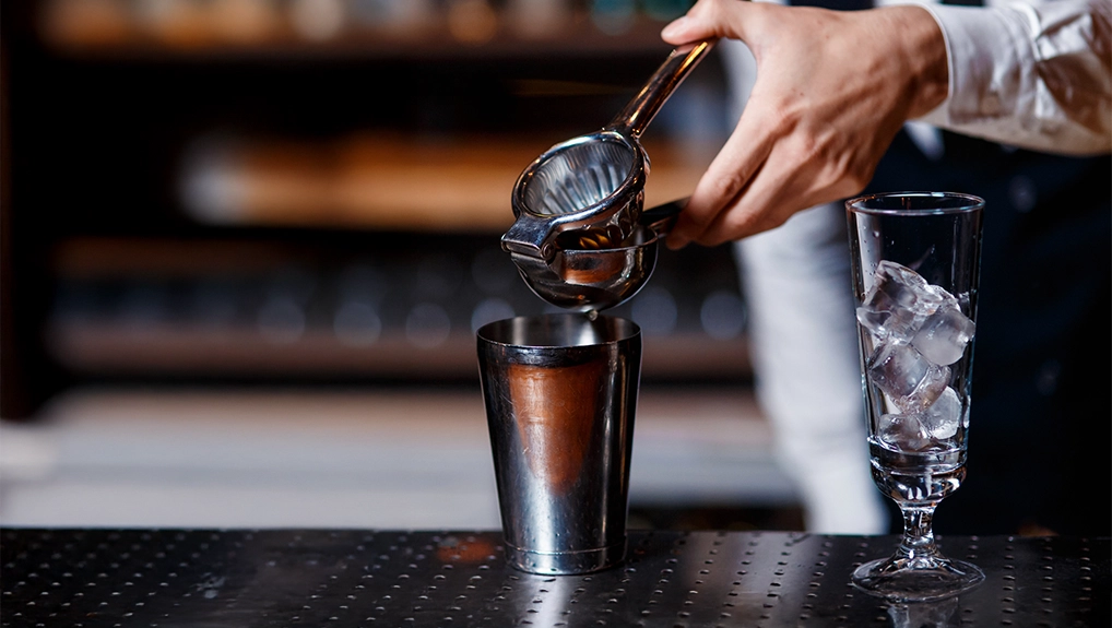 barman at work. A young bartender works with a shaker. Prepares delicious alcoholic cocktails

