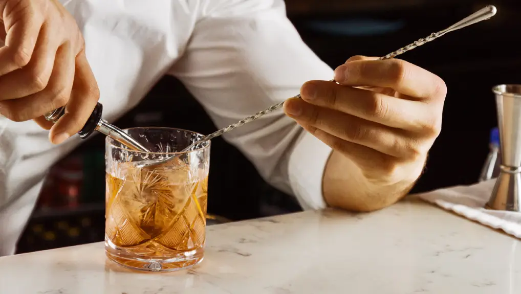 Close up image of a bar tender using a bar spoon 