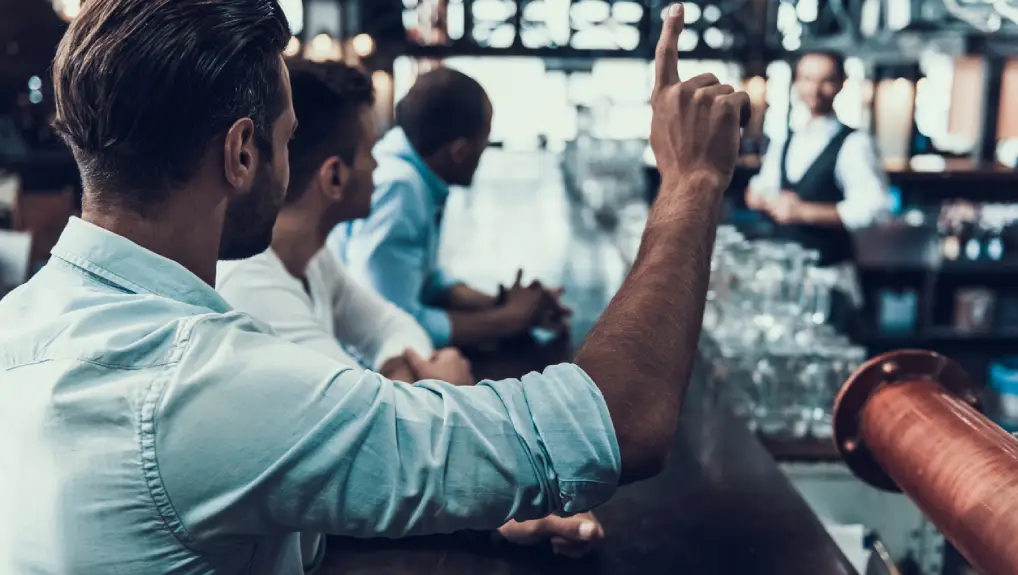 Image of a commercial bar with a optimised workflow there is a bartender and customers standing at the bar