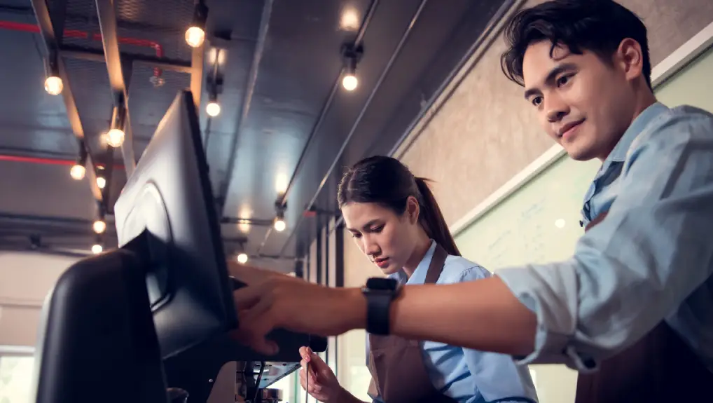 Image of two bartender and a POS till system