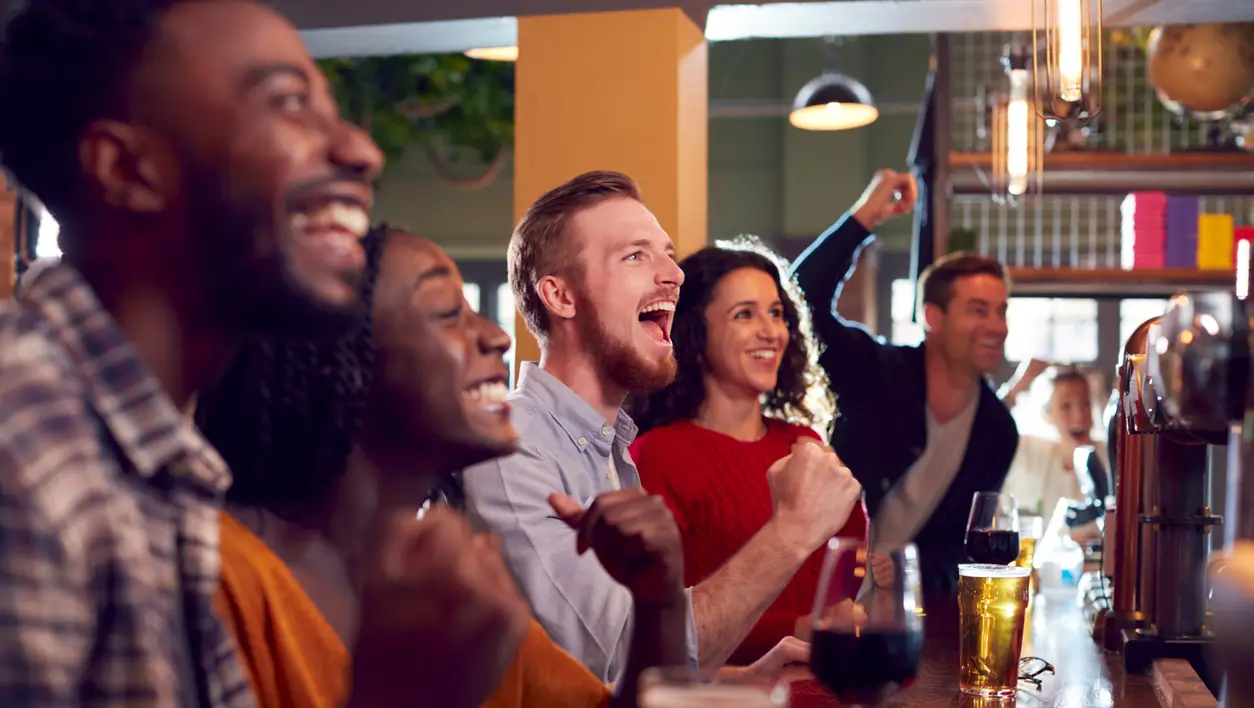 An image of a crowd gathered at a bar with drinks