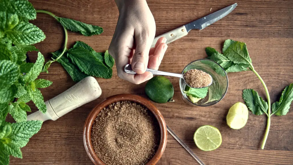 hands preparing mojito cocktail with limes and mint