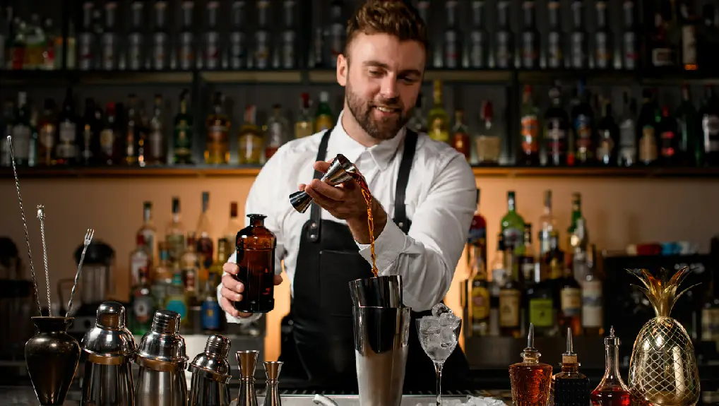 Image of a bartender making cocktails using a jigger and shaker