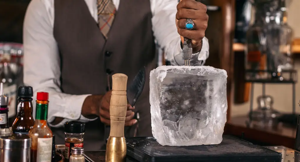 an image of a bartender  breaking an ice cube. Ice Tool Maintenance Tips for Longevity