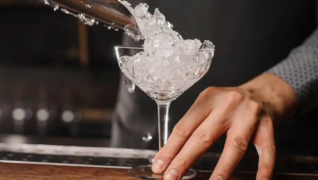 an image of ice being scooped into a cocktail glass