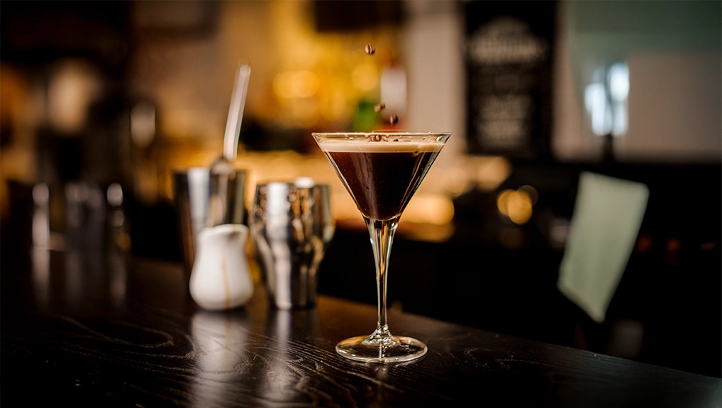 Image of classy bartender garnish martini espresso cocktail drink foam coffee bean on top bar counter