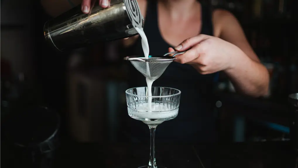 image of a hawthorne strainer being used with a shaker for a cocktail
