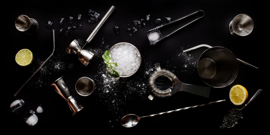 an image of Refreshing mint julep whiskey cocktail in misted frozen metal glass and bar accessories shaker jigger spoon ice sugar. Flat lay top view