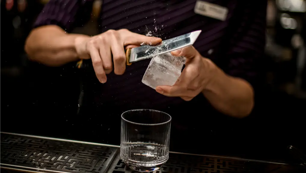 Ice being shaved down with a blade to be used in a cocktail