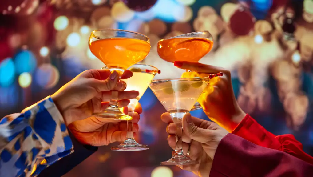 Image of  holding cocktail glasses with sweet and sour alcohol drinks against blurred background