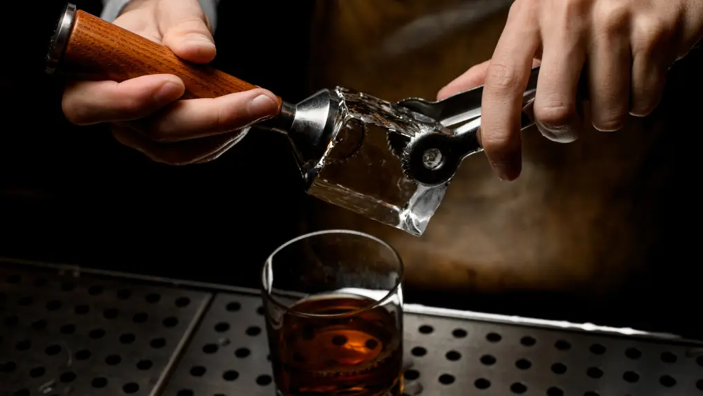 Close up image of a bartender using a ice stamp to boost the bar game.