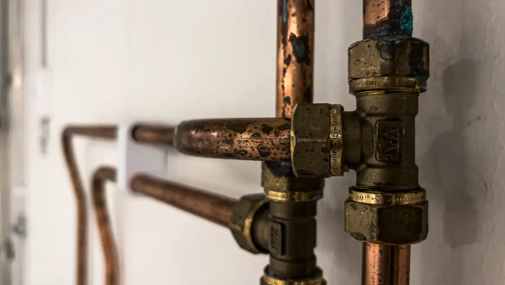 Image of Rusty copper pipes for drinking water installation background on a white wall