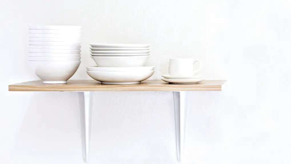 lifestyle image of stacked ceramic plates, cups, saucers and bowls on a shelf