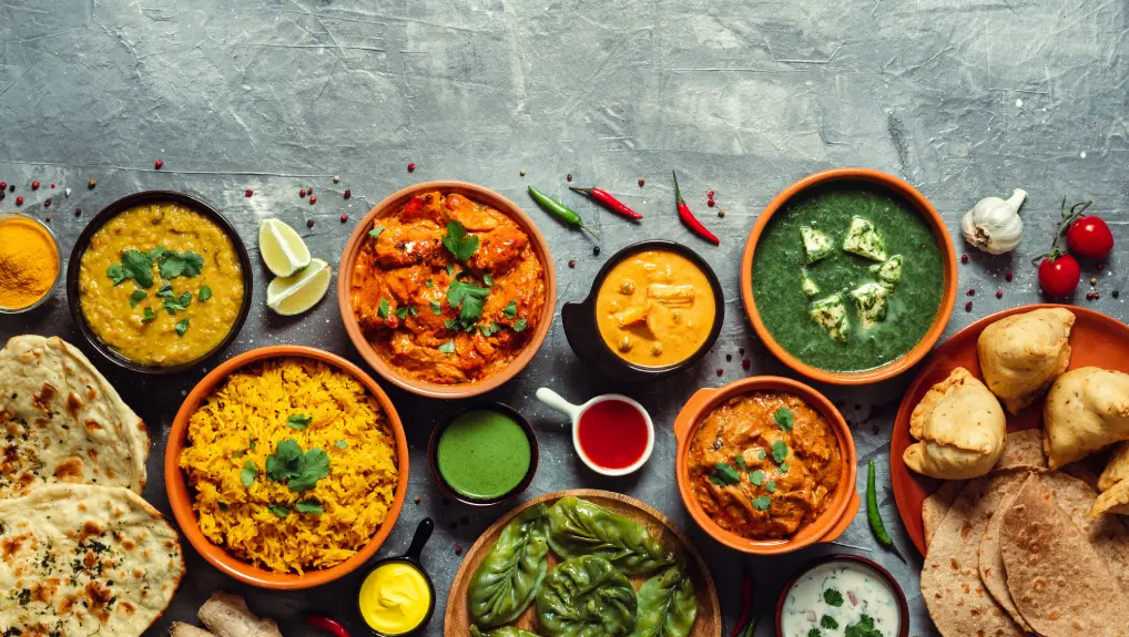 Image of Indian cuisine dishes: tikka masala, dal, paneer, samosa, chapati, chutney, spices. Indian food on gray background