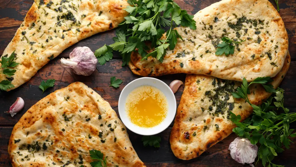 Indian naan bread with garlic butter on wooden table.

