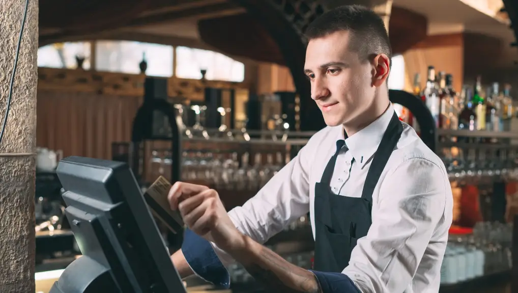 image of waiter in apron at counter with cashbox working at bar