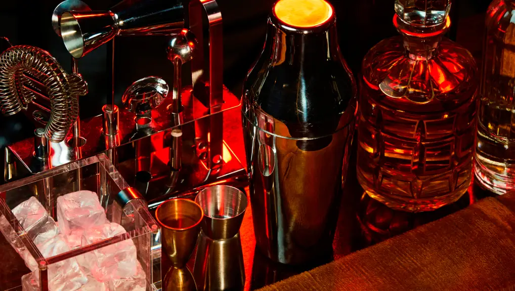 Image of bar shakers and drinks on a table, Indoors bar counter with glasses and shakers-  bar accessories guide
