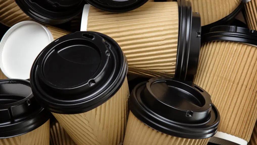 Image of a pile of disposable take away coffee/ tea cups with black lids- wholesale disposable catering supplies
