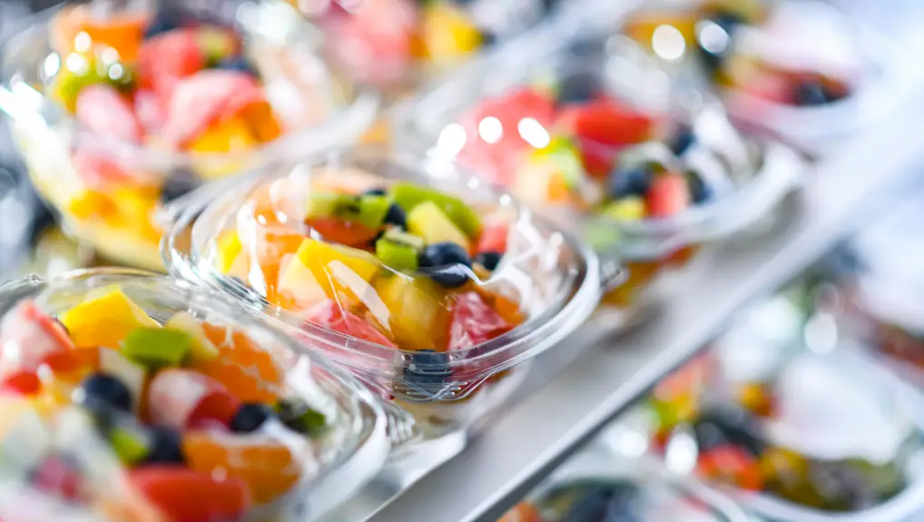 Image of Plastic boxes with pre-packaged fruit salads, put up for sale in a commercial refrigerator