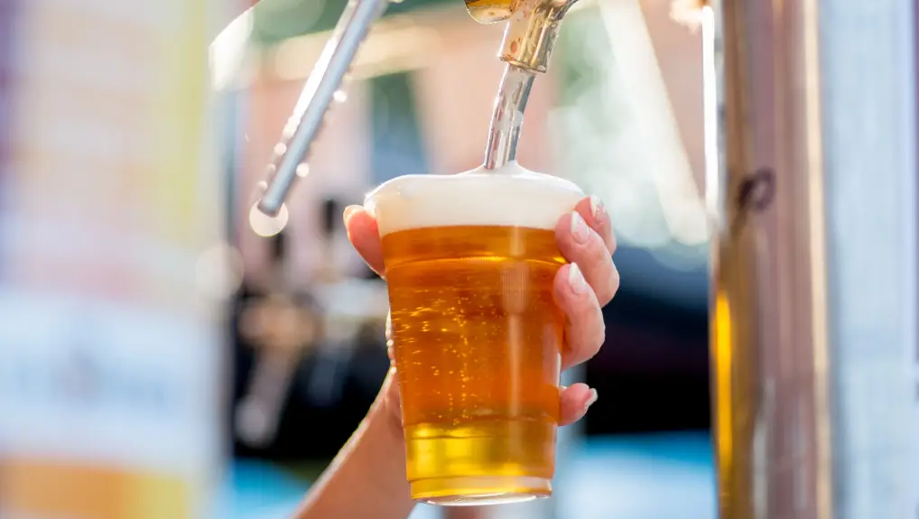 Image of  bartender pours beer into a plastic glass
