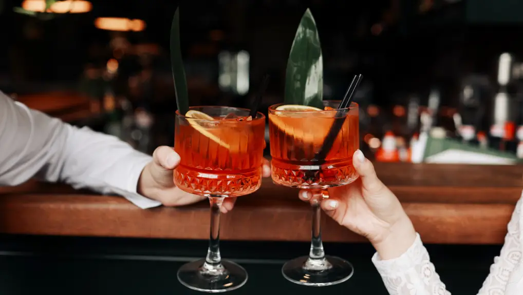 Image of hands of woman and man are clinking, cheers with glasses of Spritz cocktail