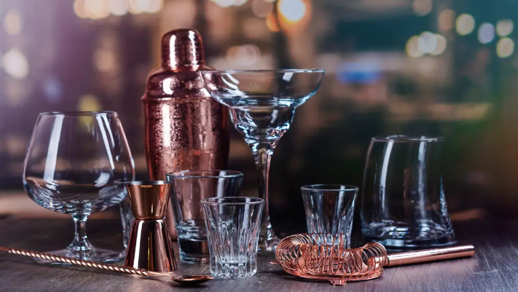 Assortment of different glass for strong alcohol drinks on bar counter over night lights background